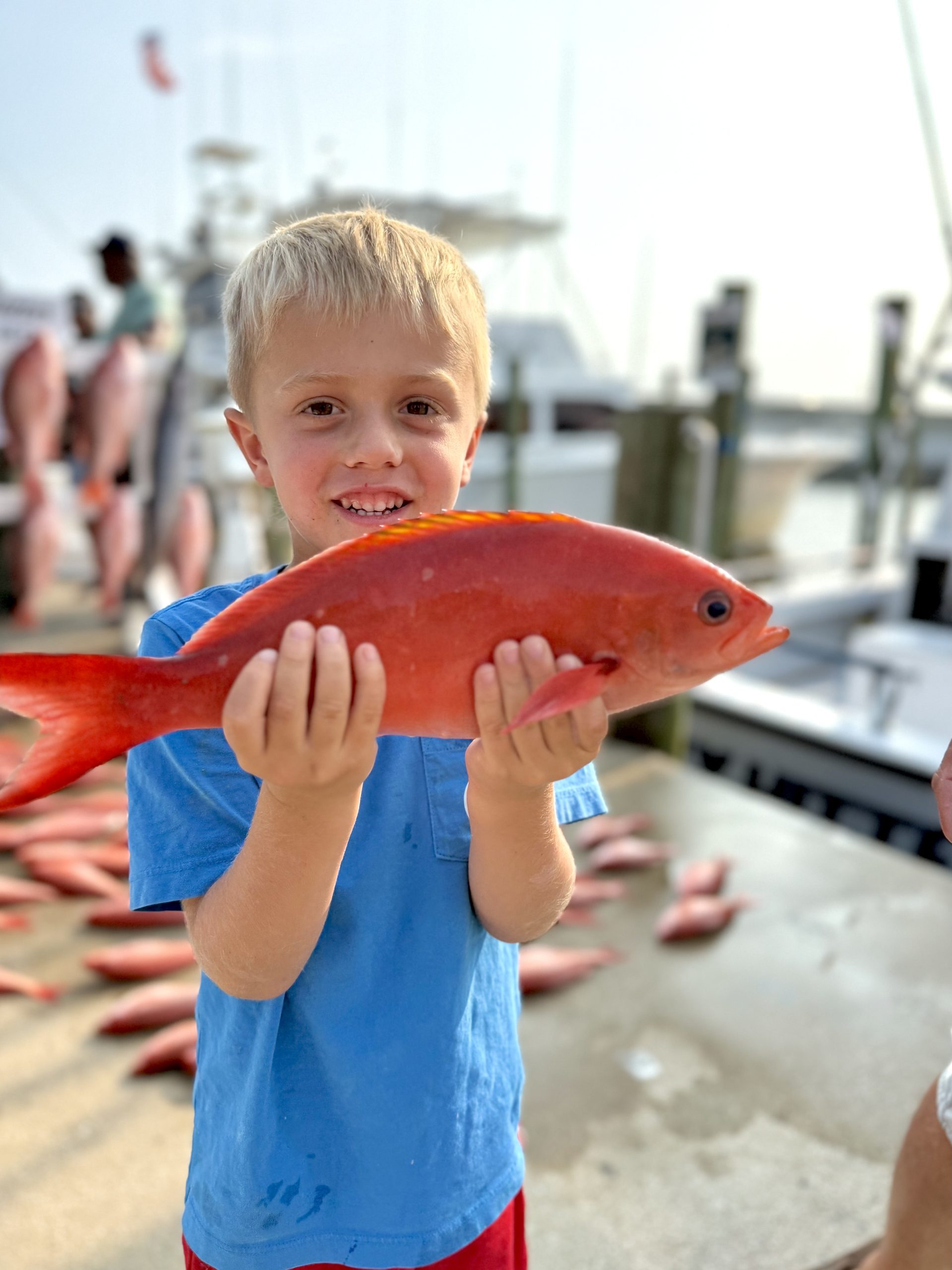 young boy holding a fish he caught while on a deep sea fishing charter with Heavy Hitter Charters in Panama City